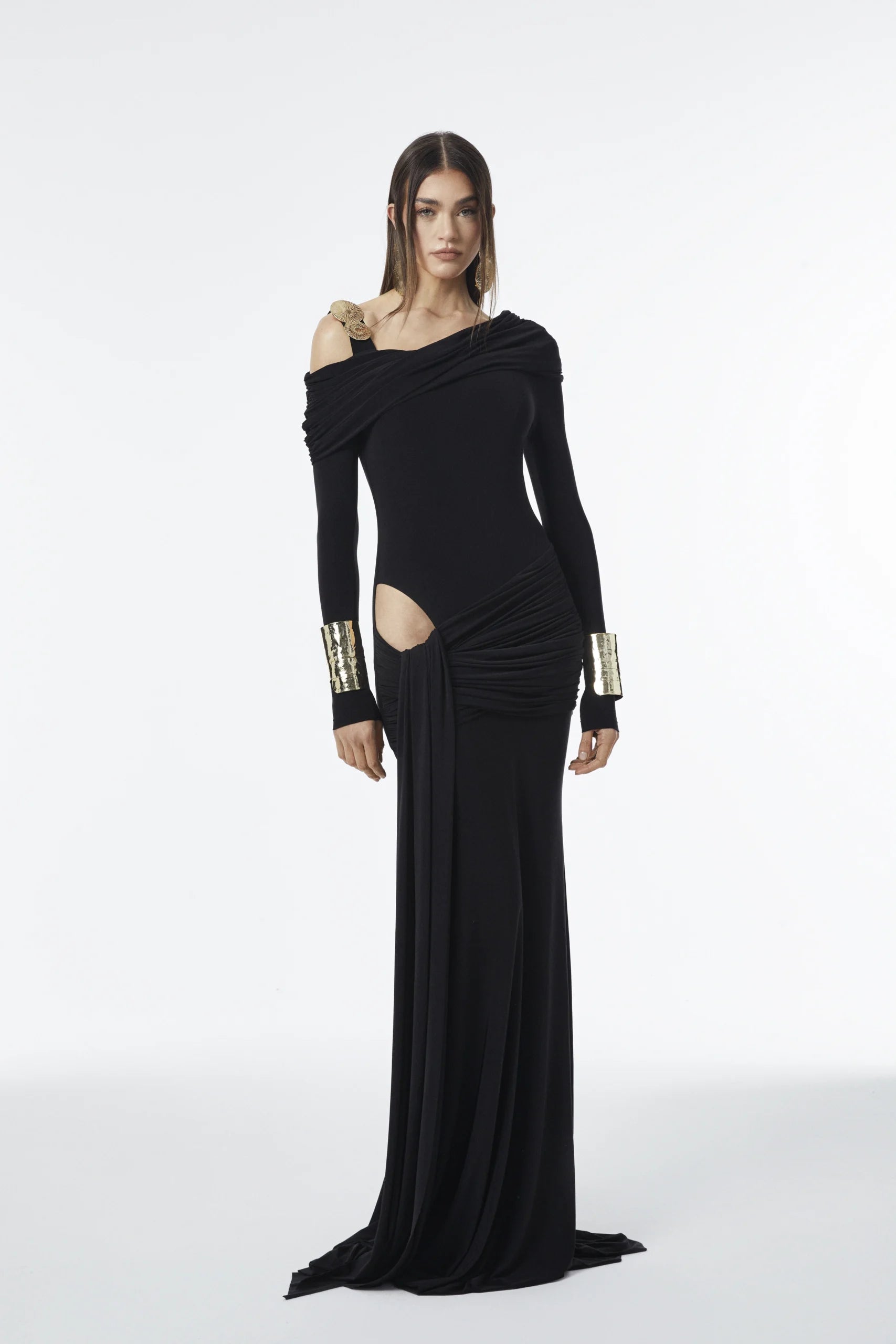 Asymmetric one-strap dress with gold detail, long sleeves, front draping, and side peekaboo cutout.